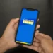 Texto alternativo: "Pessoa segurando um smartphone com a tela mostrando o logo do CadÚnico 2025