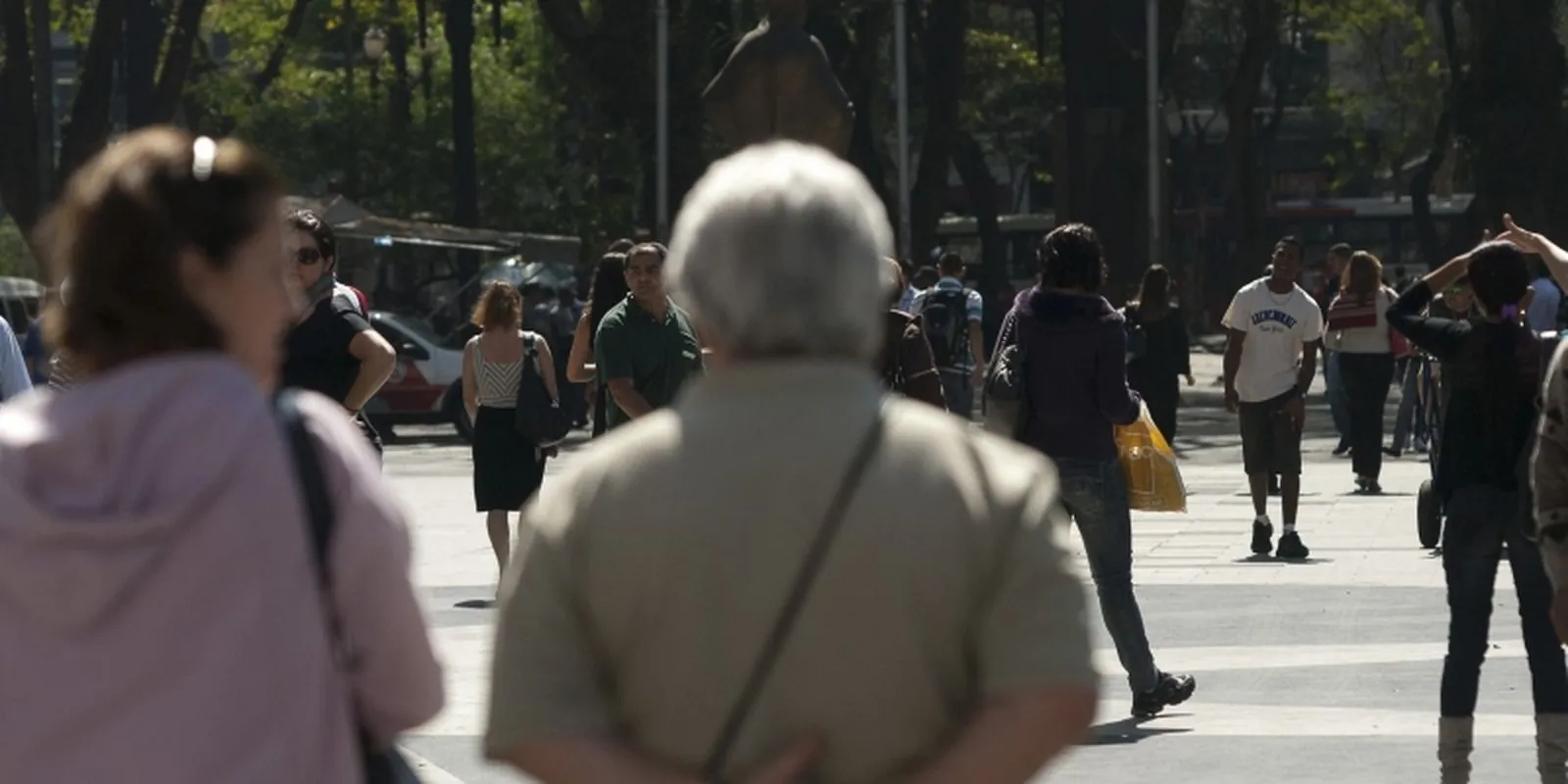 Idoso caminhando entre pedestres em via pública movimentada