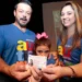 Família feliz segurando a Carteira de Identificação do Autista, mostrando a importância do documento.
