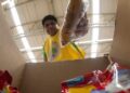 Homem colocando alimentos em uma caixa, representando o aumento dos preços da cesta básica.