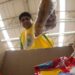 Homem colocando alimentos em uma caixa, representando o aumento dos preços da cesta básica.
