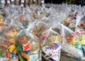 Diversas cestas básicas embaladas em sacos plásticos transparentes, prontas para distribuição.