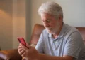 Homem idoso usando celular com atenção, representando cuidados ao navegar na internet.