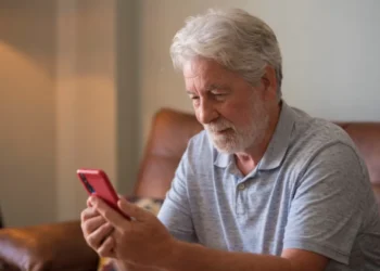 Homem idoso usando celular com atenção, representando cuidados ao navegar na internet.