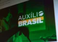 Pessoas consultando informações sobre o programa Auxílio Brasil em um dispositivo eletrônico.
