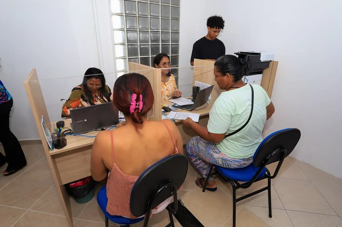 Atendimento presencial no CRAS, com cidadãos sendo assistidos por profissionais durante o processo de cadastramento.