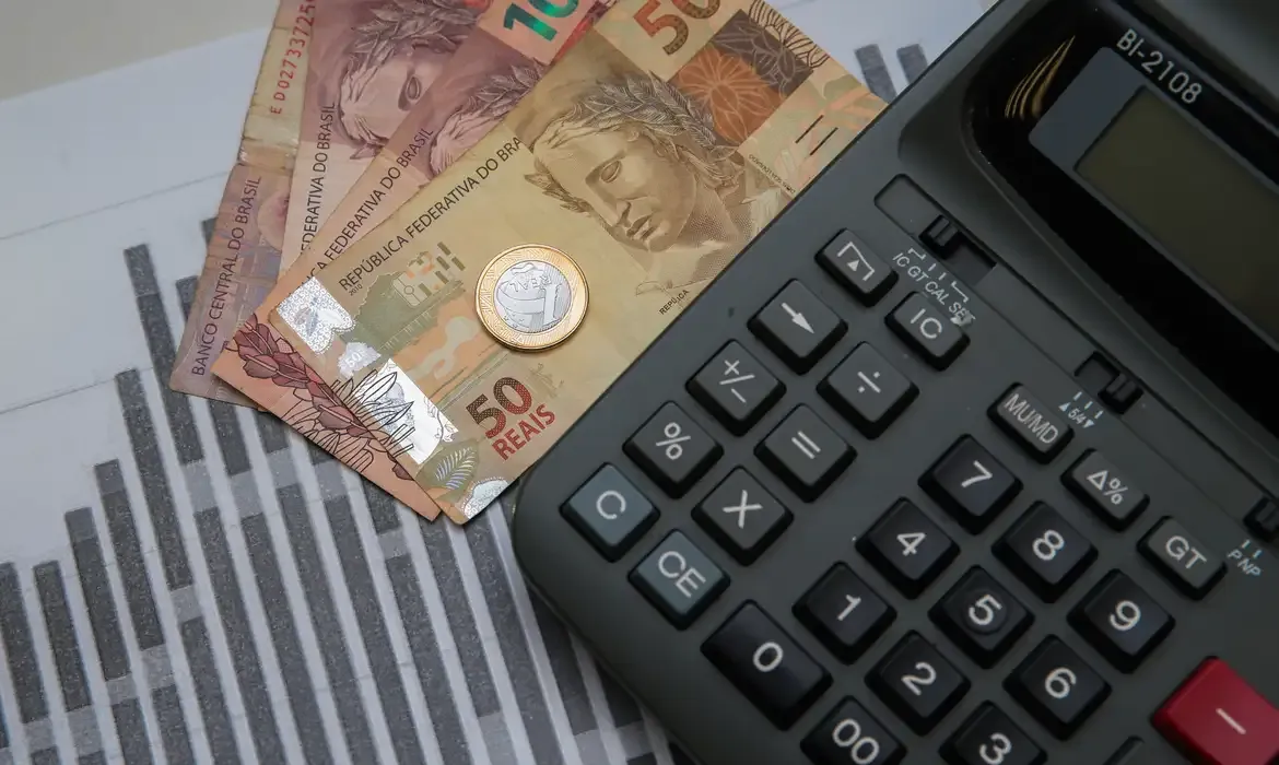 "Notas de dinheiro e calculadora, ilustrando o cálculo do imposto de renda ou restituição"