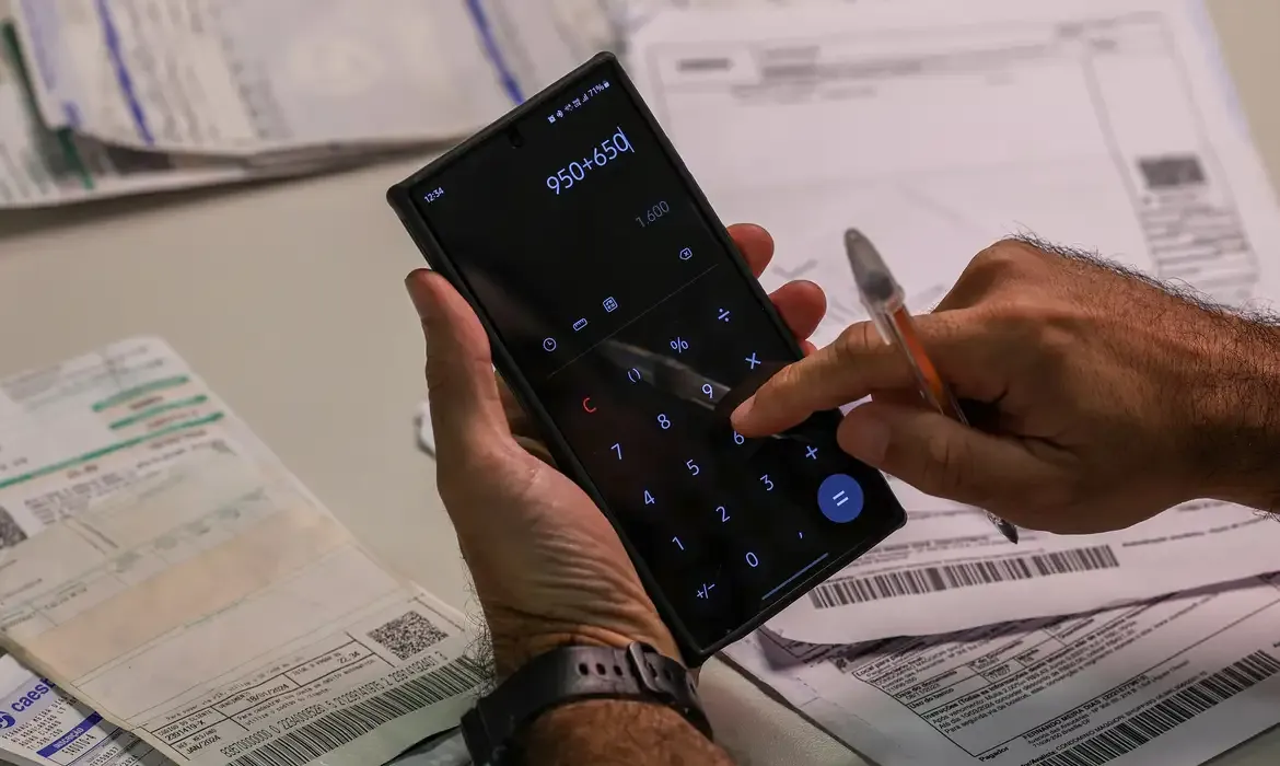"Pessoa utilizando calculadora no celular para renegociar dívidas com instituições financeiras"