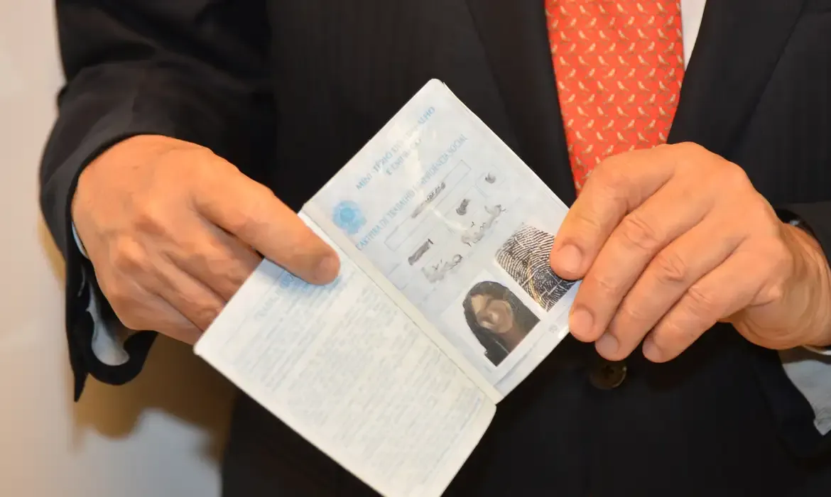 Foto de uma pessoa segurando um documento de identidade, essencial para comprovar condições para o seguro.