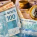 Cédulas de real e moedas ilustrando o pagamento de auxílios confirmados em maio.