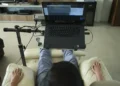 Pessoa usando laptop em cadeira reclinável, adaptada para conforto devido à esclerose múltipla.