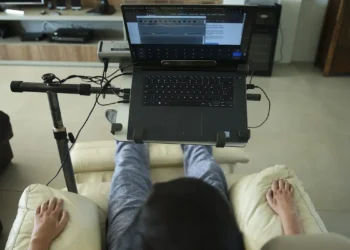 Pessoa usando laptop em cadeira reclinável, adaptada para conforto devido à esclerose múltipla.