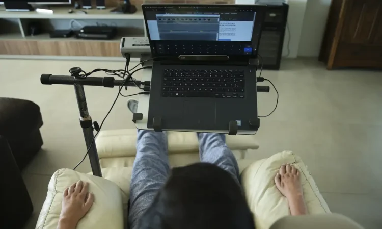 Pessoa usando laptop em cadeira reclinável, adaptada para conforto devido à esclerose múltipla.