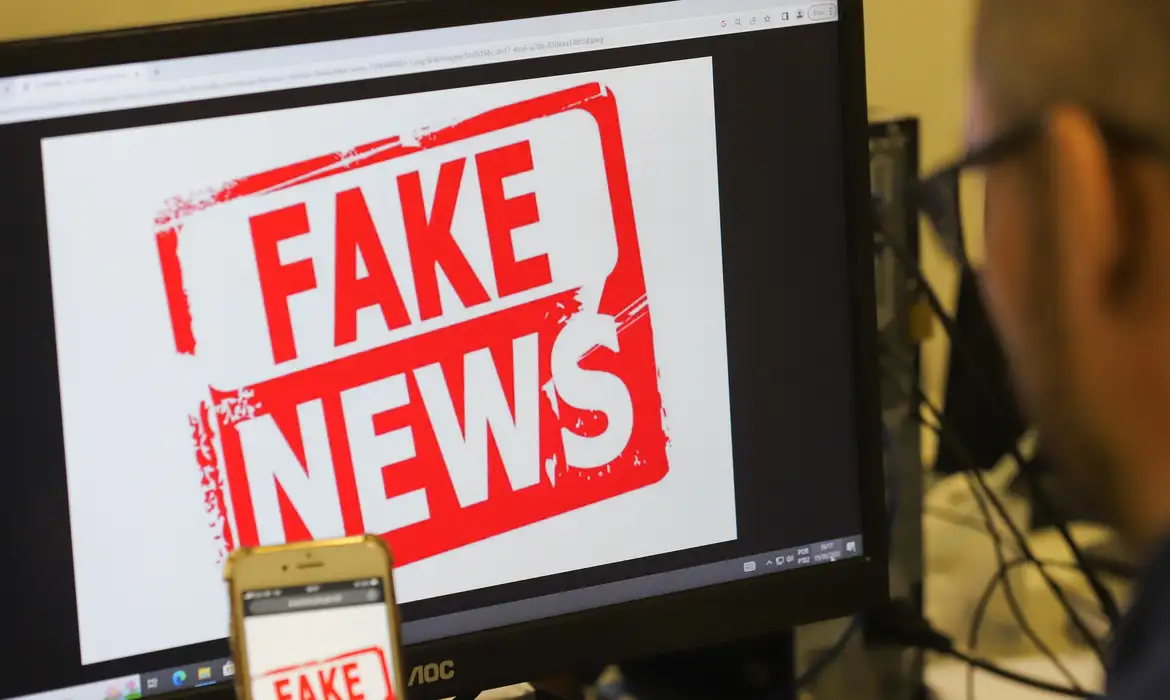 Selo vermelho com a frase "Fake News" em letras grandes, indicando notícia falsa.