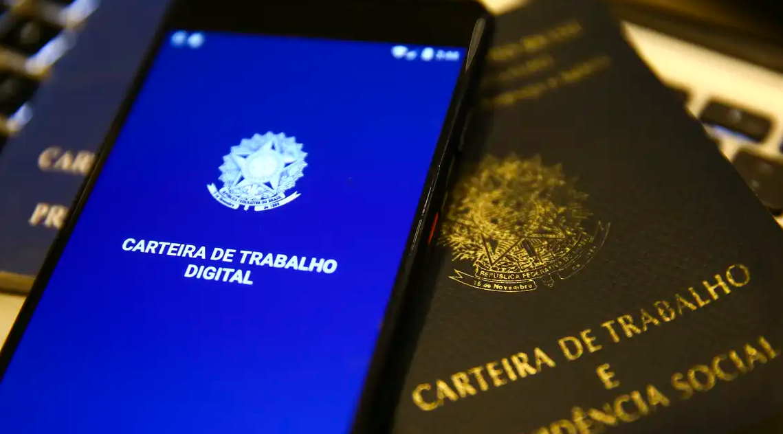 Aplicativo da Carteira de Trabalho Digital exibido em celular ao lado de documentos físicos