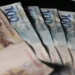 Notas de R$ 100 e R$ 200 dispostas em um fundo preto, representando o valor de R$ 1.518,00 em dinheiro.