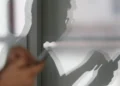 Sombra de pessoa usando celular, simbolizando ações suspeitas.