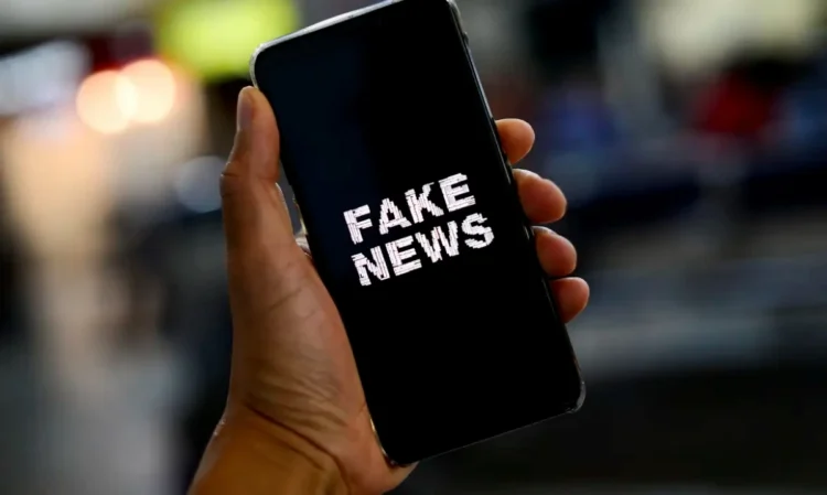 Mão segurando smartphone com a tela exibindo a mensagem "Fake News"