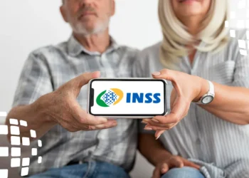 Casal idoso mostrando celular com o logo do INSS, representando atualização de dados cadastrais pela internet.