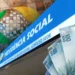 Imagem do INSS com notas de R$ 100 e a sede do Instituto Nacional do Seguro Social, representando o pagamento de até R$ 8.157,41.
