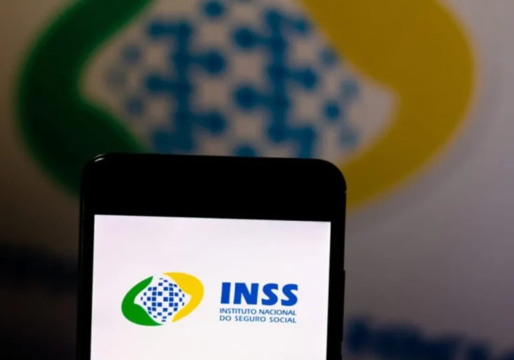 Logo do INSS exibido na tela de um smartphone com fundo desfocado, em referência à suspensão de novos empréstimos consignados.
