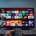 Controle remoto apontando para uma smart TV com diversos ícones de aplicativos de streaming, representando o uso de IPTV.