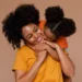 Mãe e filha sorrindo juntas em um abraço carinhoso, com um fundo suave de cor quente.