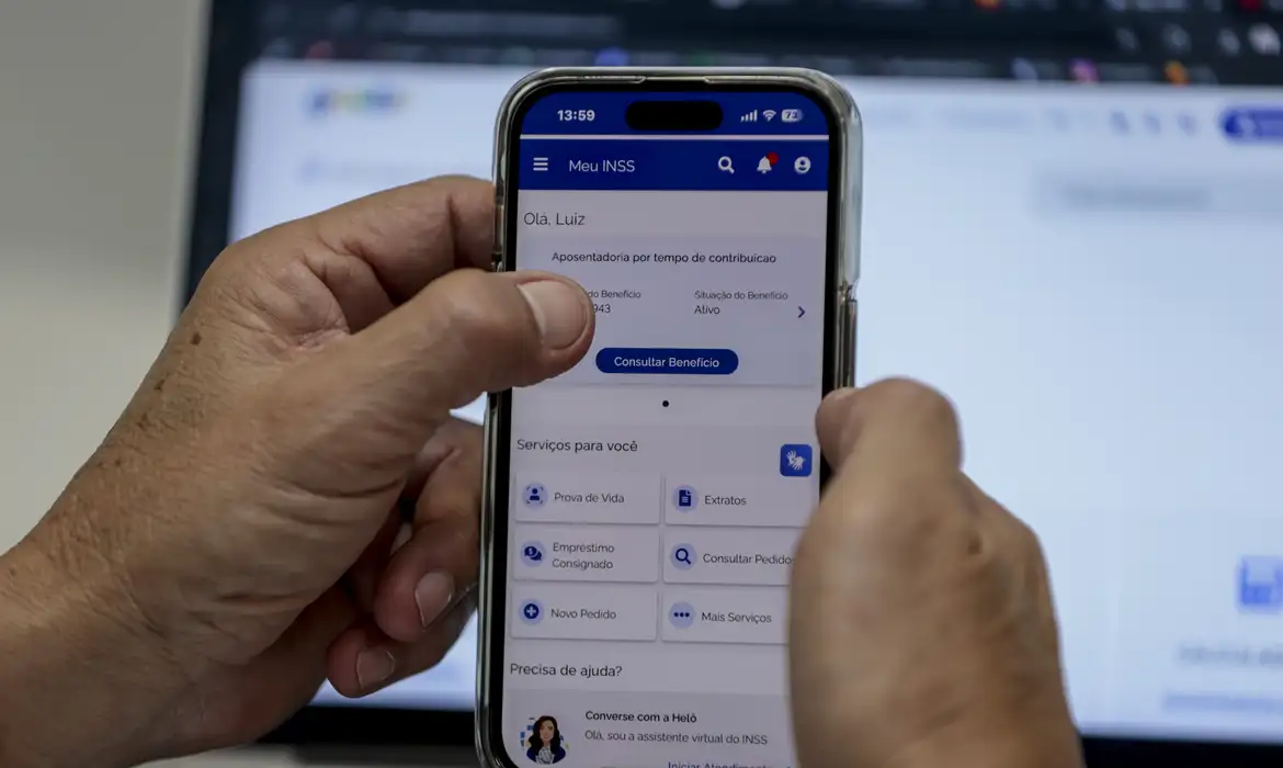 Pessoa segurando celular e usando o aplicativo Meu INSS para consultar benefícios.