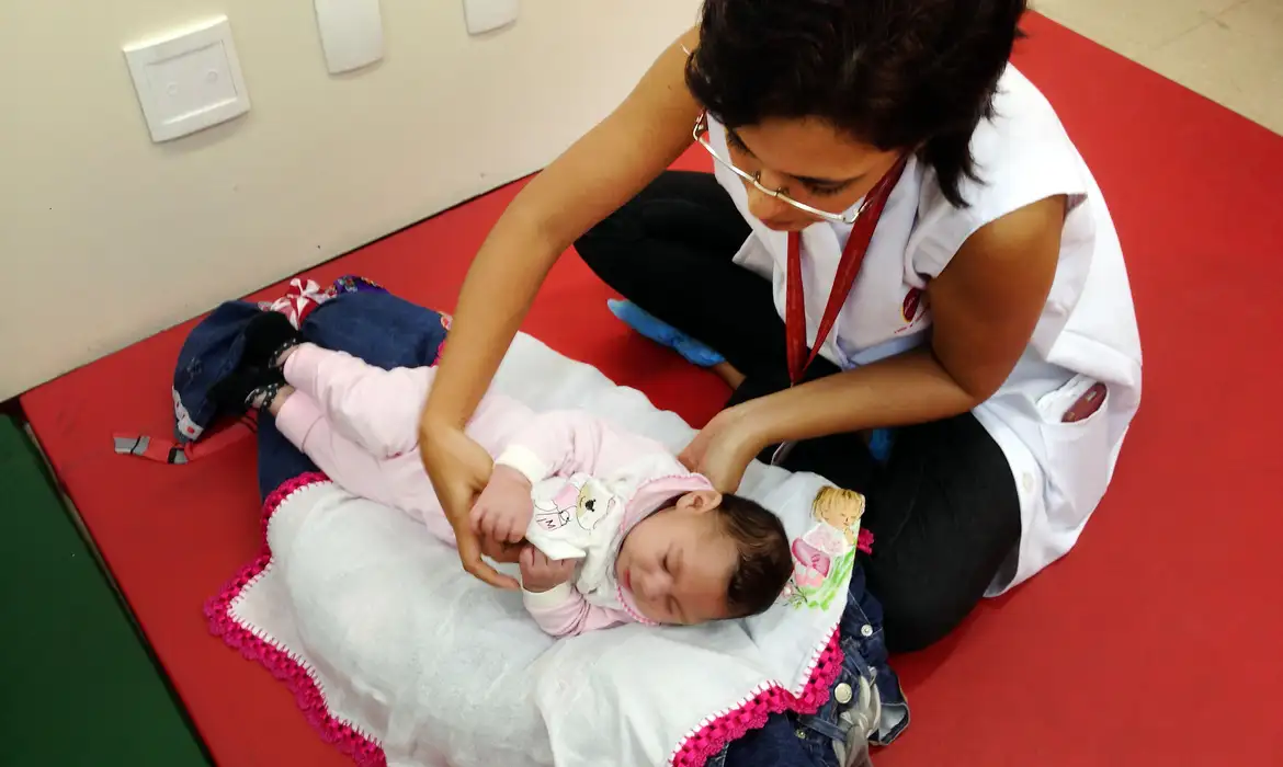 Profissional de saúde cuidando de bebê com deficiência causada pelo vírus Zika.