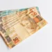 Cédulas de 50 reais simbolizando benefício financeiro liberado no Brasil.