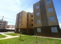Bloco de apartamentos populares com céu azul, destacando a importância do acesso à moradia social.