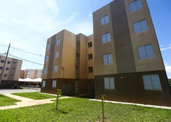Bloco de apartamentos populares com céu azul, destacando a importância do acesso à moradia social.