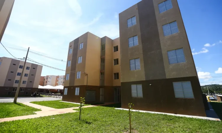 Bloco de apartamentos populares com céu azul, destacando a importância do acesso à moradia social.