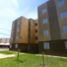 Bloco de apartamentos populares com céu azul, destacando a importância do acesso à moradia social.