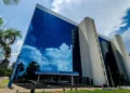 Prédio do INSS refletindo o céu, com a fachada principal da Previdência Social em destaque.