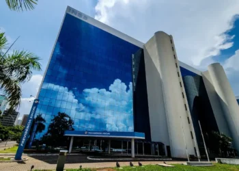 Prédio do INSS refletindo o céu, com a fachada principal da Previdência Social em destaque.