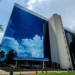 Prédio do INSS refletindo o céu, com a fachada principal da Previdência Social em destaque.