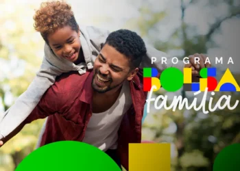 Homem sorridente carregando criança no parque, representando felicidade e união familiar no programa Bolsa Família 2025.