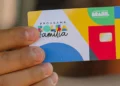 "Cartão do Programa Bolsa Família sendo segurado por uma pessoa, representando a transição tranquila para o mercado de trabalho."