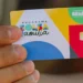 "Cartão do Programa Bolsa Família sendo segurado por uma pessoa, representando a transição tranquila para o mercado de trabalho."