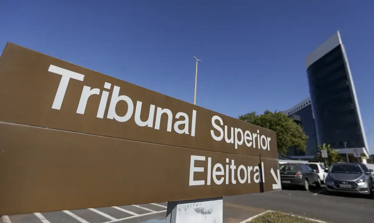 Placa indicativa do Tribunal Superior Eleitoral em área urbana, com carros estacionados ao fundo.