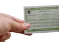 Cartão de título eleitoral brasileiro sendo segurado por uma mão, simbolizando a importância da regularização do título de eleitor.