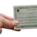 Cartão de título eleitoral brasileiro sendo segurado por uma mão, simbolizando a importância da regularização do título de eleitor.