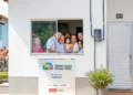Família sorridente na janela de uma casa do programa Minha Casa Minha Vida, destacando o Residencial Angelin em 2025.