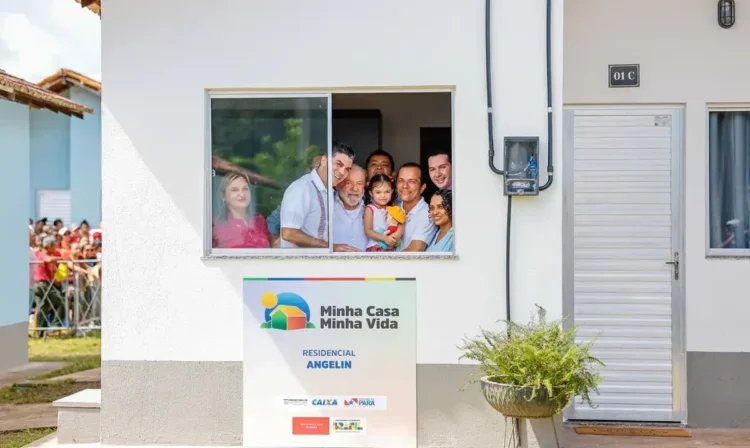 Família sorridente na janela de uma casa do programa Minha Casa Minha Vida, destacando o Residencial Angelin em 2025.
