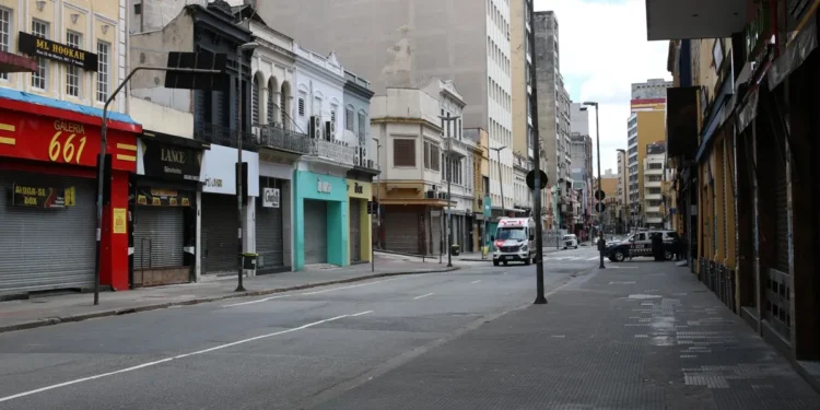 Rua deserta durante o feriado de 20 de novembro, com lojas fechadas, refletindo a aplicação do ponto facultativo.
