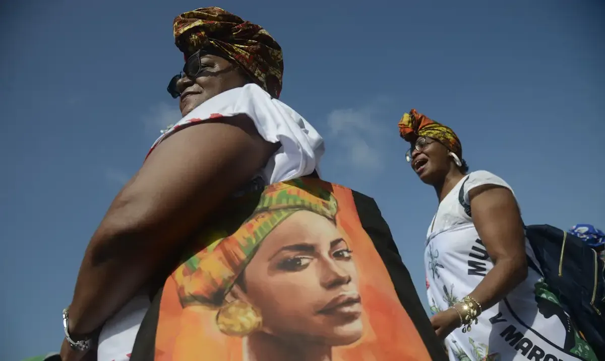 Mulheres vestindo roupas com estampas afro-brasileiras durante o Dia da Consciência Negra, refletindo o engajamento cultural e social.
