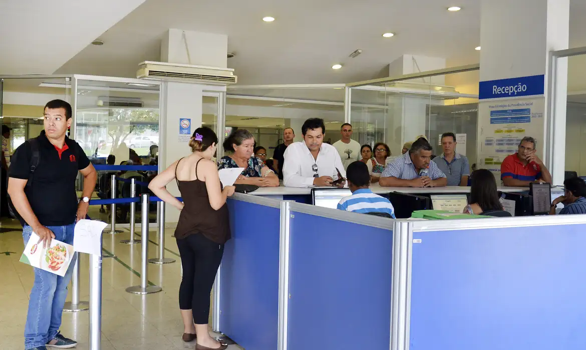 Pessoas aguardando atendimento na recepção de um órgão de previdência social.