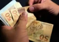 Pessoa contando cédulas de R$ 50, ilustrando o pagamento de valores por meio de PIX.