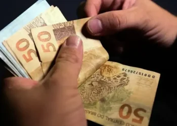 Pessoa contando cédulas de R$ 50, ilustrando o pagamento de valores por meio de PIX.